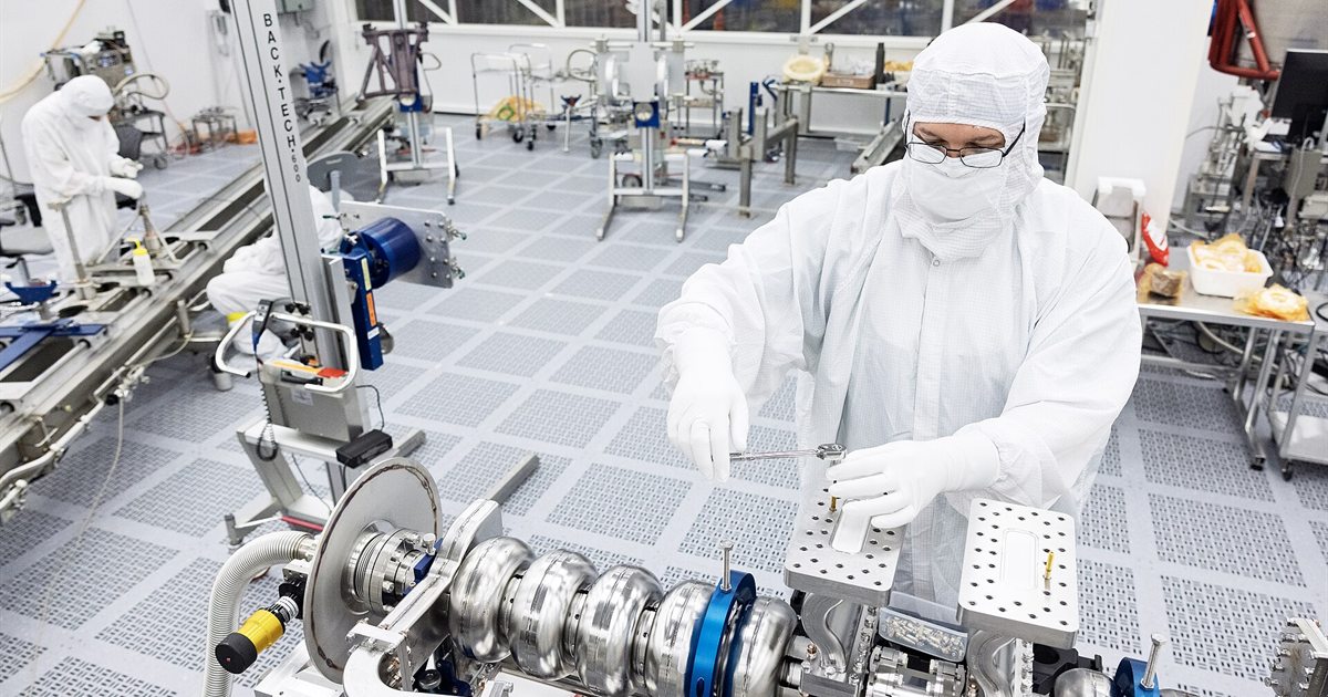 A technician in a clean room suit working on equipment