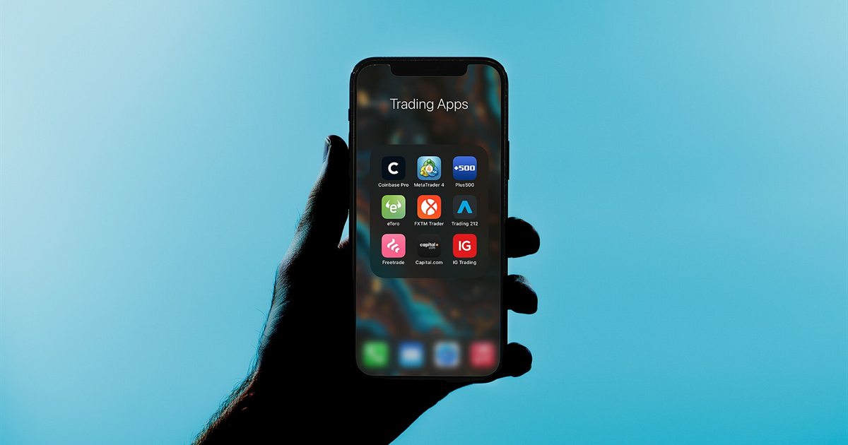 A hand holding a smartphone showing a folder of trading apps
