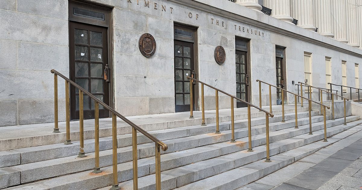 Stone steps and brass handrails leading up to an entrance of the US Department of the Treasury building in Washington, D.C.