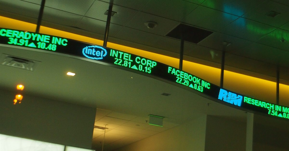 An electronic stock ticker scrolling share prices across a lobby wall