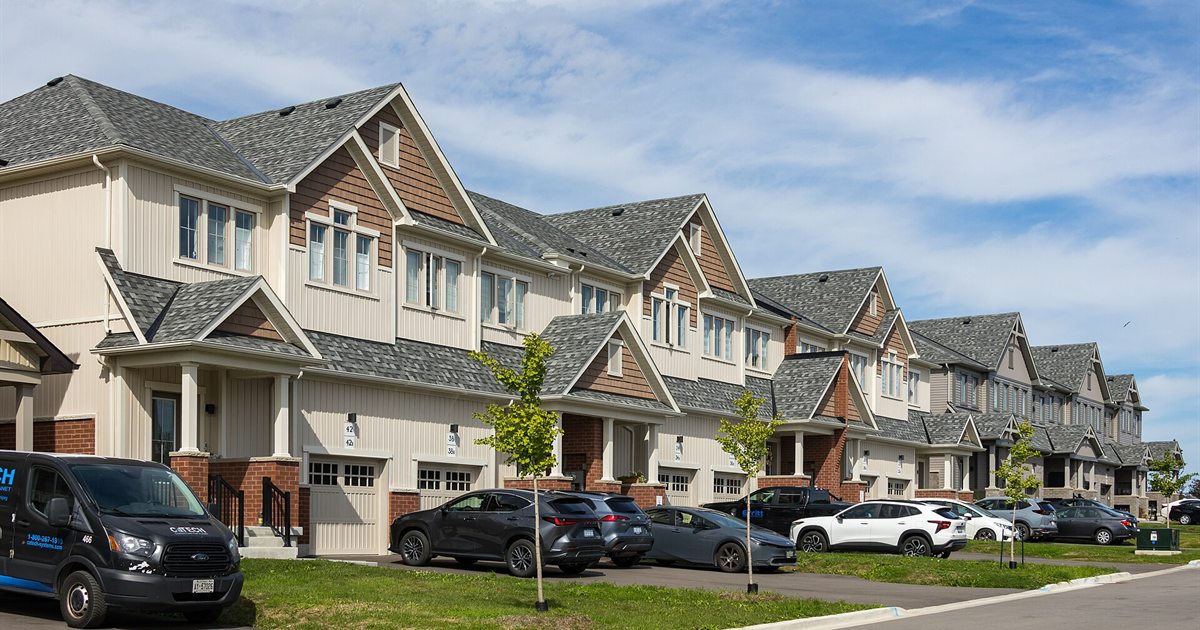 A row of new two-storey suburban houses with cars in the driveways in Newcastle, Ontario