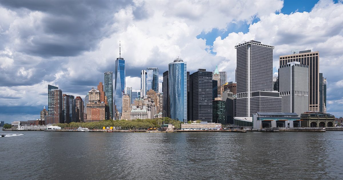 The Lower Manhattan skyline under dark storm clouds, seen from New York Harbor