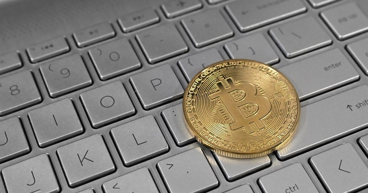 A gold-coloured Bitcoin token resting on a laptop keyboard