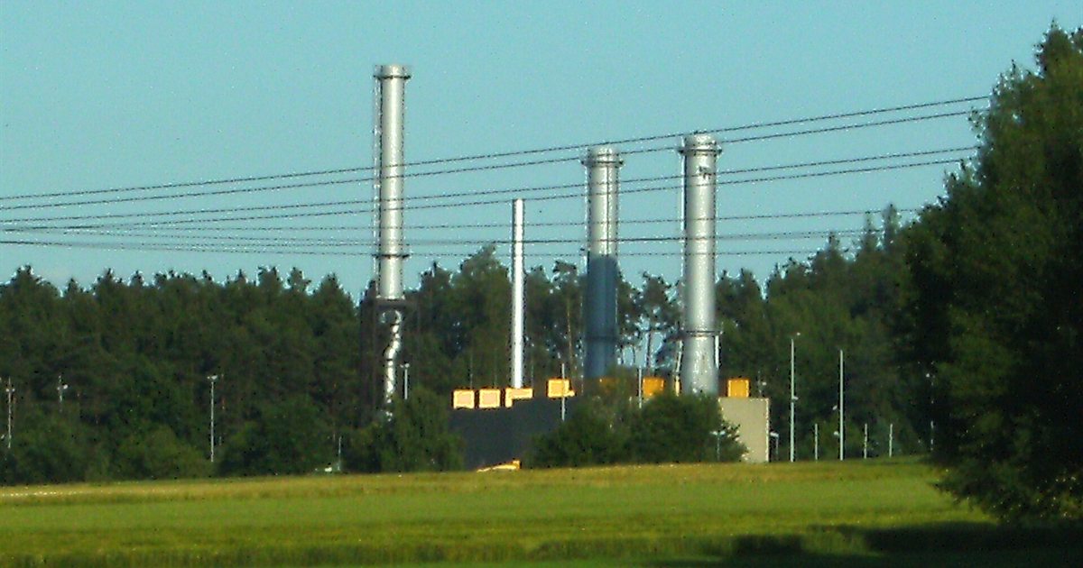 A natural gas compressor station with tall exhaust stacks beside a forest in Rothenstadt, Germany