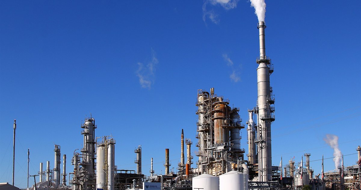 Distillation towers and a smokestack at an oil refinery in Three Rivers, Texas, under a blue sky