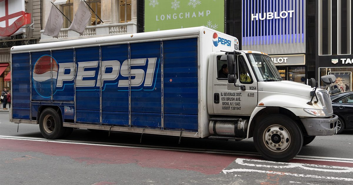 A blue Pepsi delivery truck with the Pepsi logo on its side driving along a city street