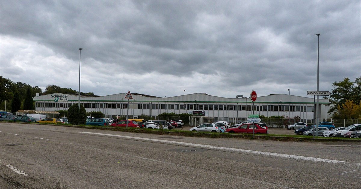 A Schneider Electric factory and office building in Aubenas, France, seen from the road under a cloudy sky