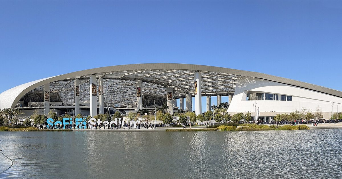 SoFi Stadium in Inglewood, California, with its curved translucent roof reflected in a lake