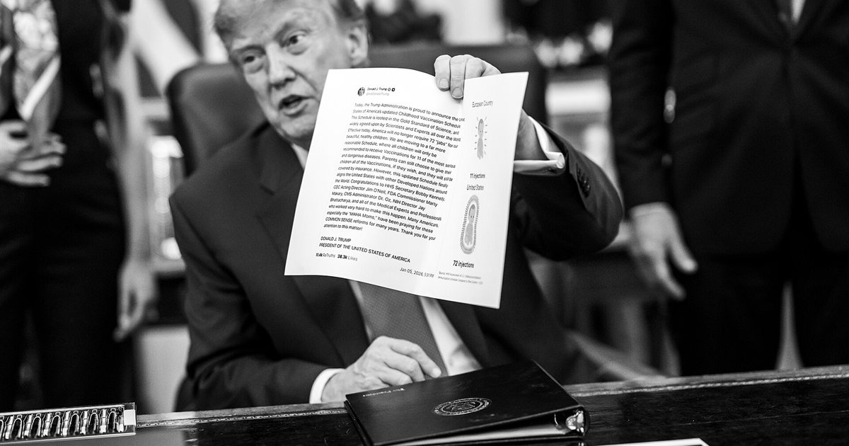 President Trump holding up a signed executive order in the Oval Office